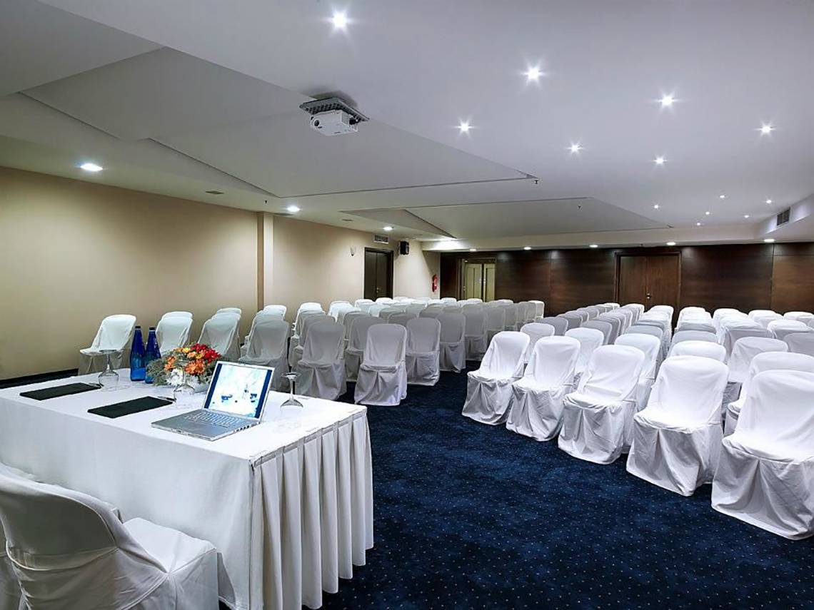 Konferenzraum im Michelangelo Resort & Spa mit gedecktem Tisch, Laptop und gedeckten Stühlen.