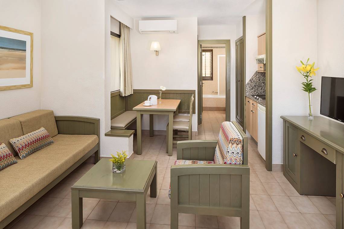 Innenansicht einer Suite im HD Parque Cristobal Hotel mit Wohnzimmer, Essbereich und Fernseher.
