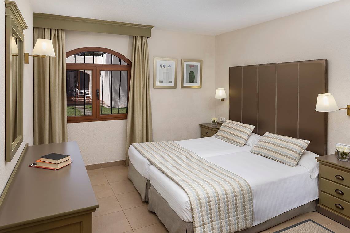 Innenansicht eines Doppelzimmers im HD Parque Cristobal Hotel mit zwei Betten, Schreibtisch und Aussichtsfenster.
