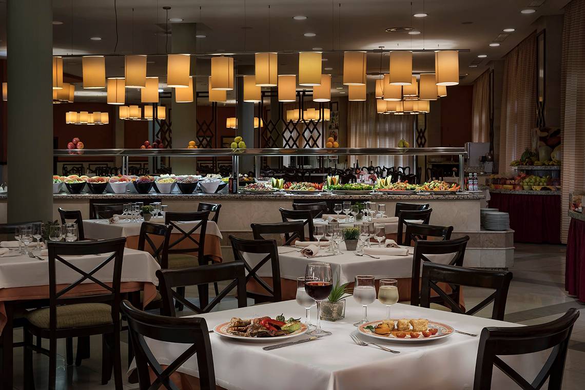Foto des Innenbereichs des Restaurants im HD Parque Cristobal Hotel mit gedeckten Tischen und Buffet.