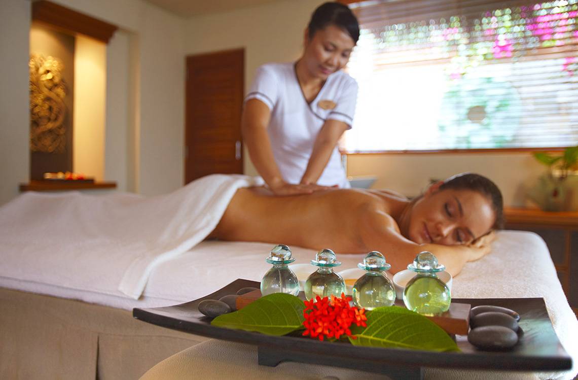 Massage Behandlung im Baros Maldives Resort mit einer Frau, die auf einem Massagetisch liegt.