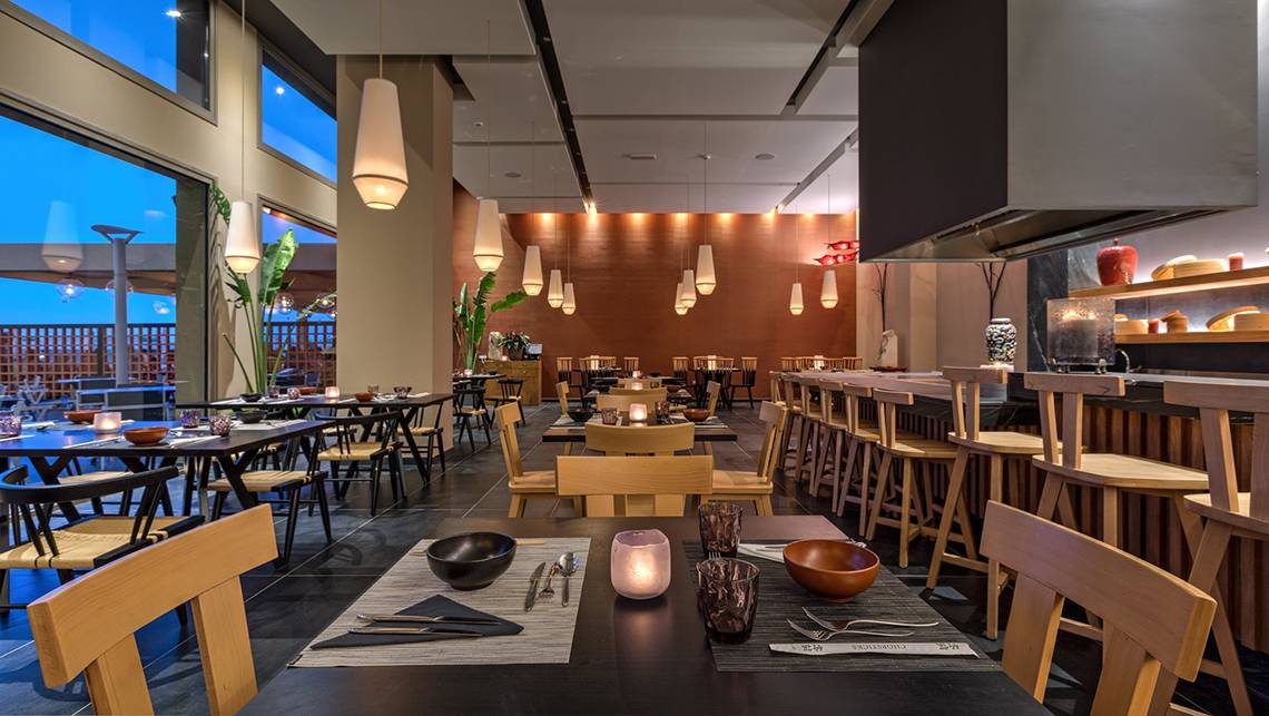 Innenansicht des Restaurants im Amada Colossos Resort mit Tischen, Stühlen und Kerzen.