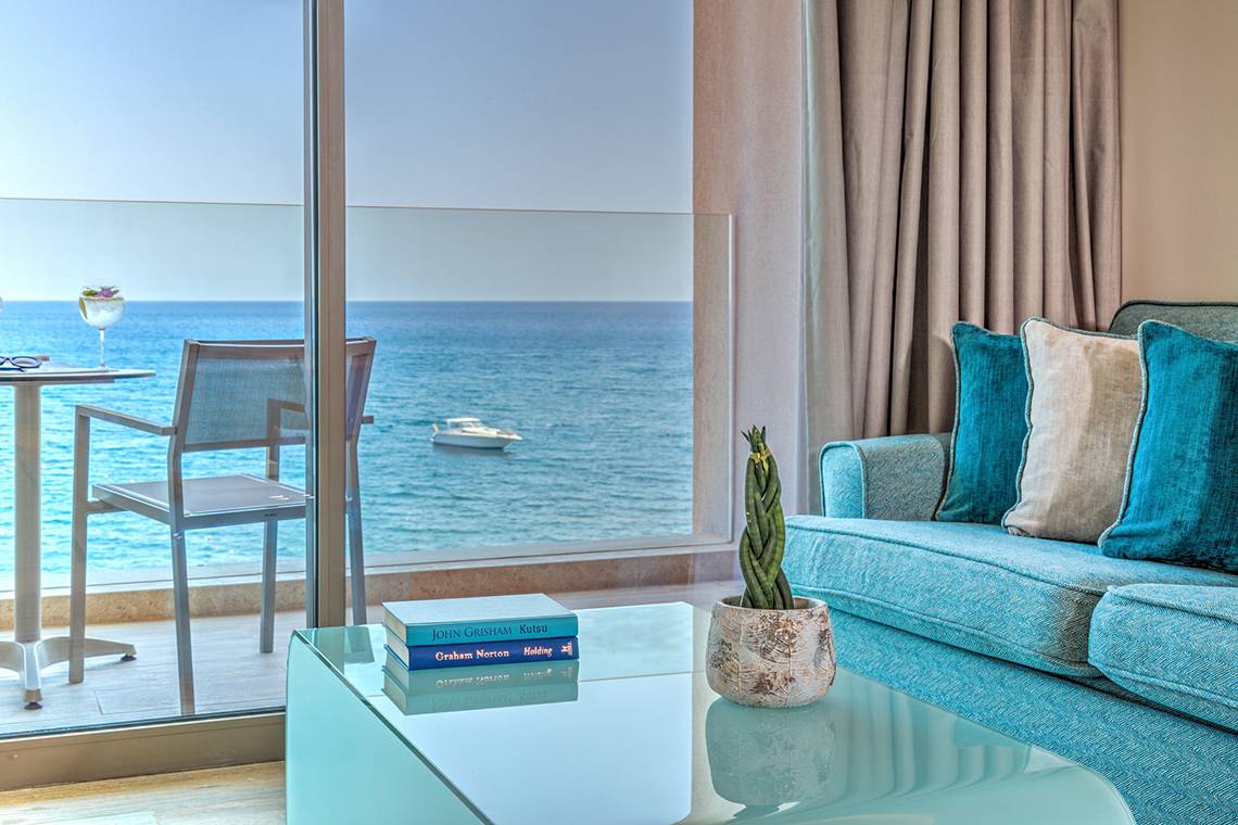 Hotelzimmer mit Meerblick: Couch, Tisch und Bücher auf dem Glastisch.