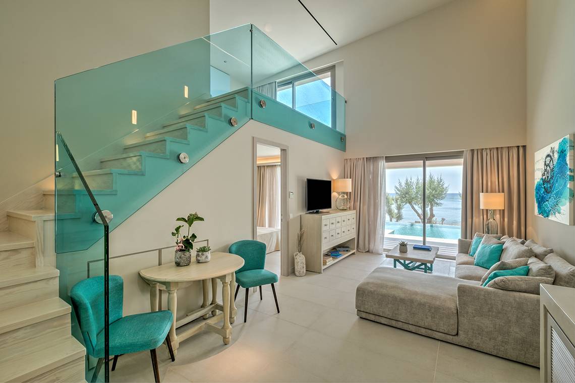 Wohnzimmer des Amada Colossos Resorts mit Glastreppe und Meerblick.
