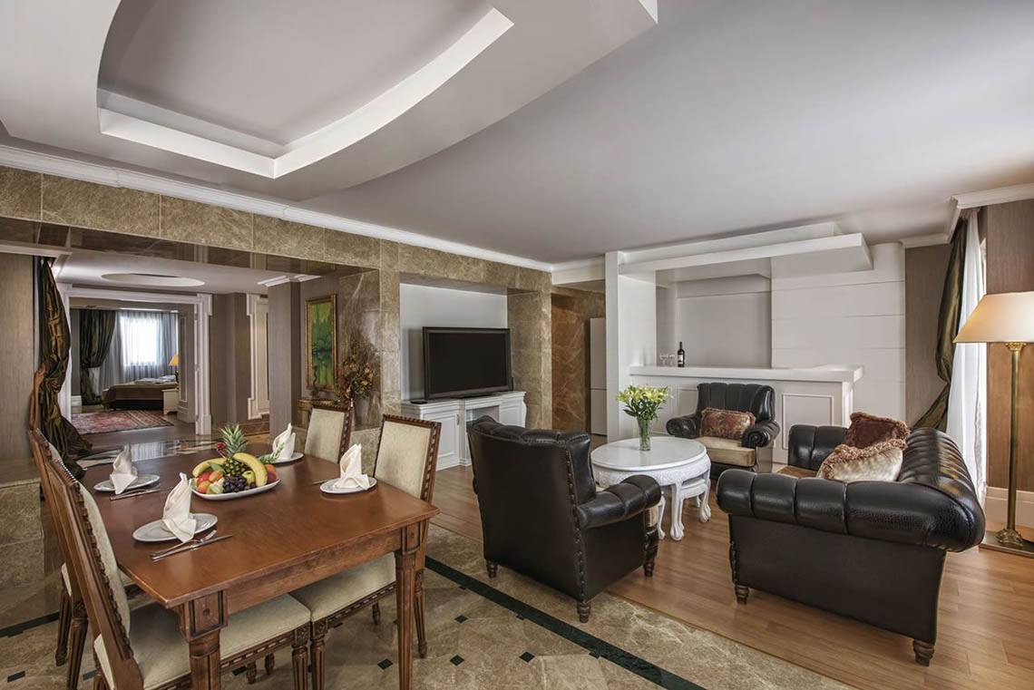 Wohnbereich des Delphin Diva Premiere Hotels mit Esstisch, Couch und Fernseher.