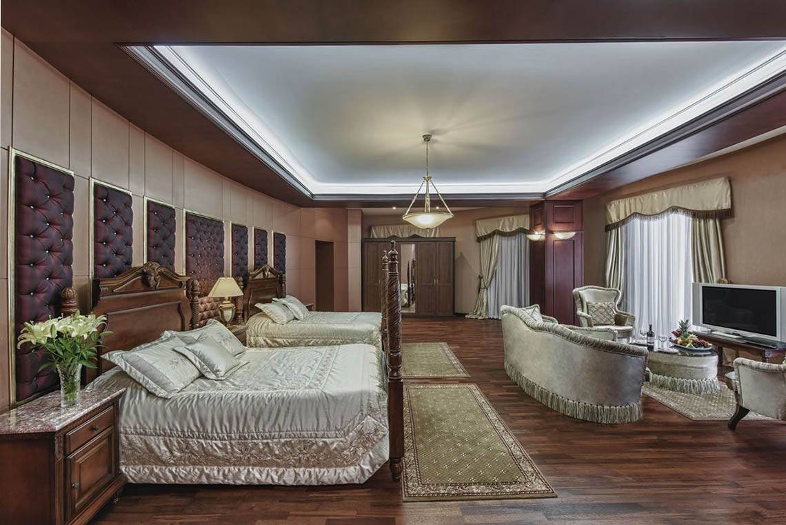 Schlafzimmer im Delphin Diva Premiere Hotel mit zwei Betten, Wohnzimmerbereich und Fernseher.