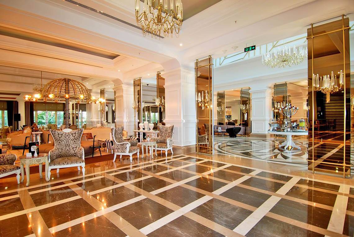 Das elegante Foyer des Delphin Diva Premiere Hotels mit Marmorboden und Kristallkronleuchtern.