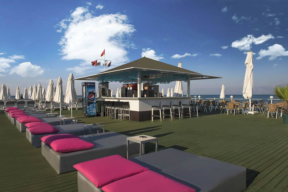 Loungebereich des Delphin Diva Premiere Hotels mit Sonnenliegen und einer Bar.