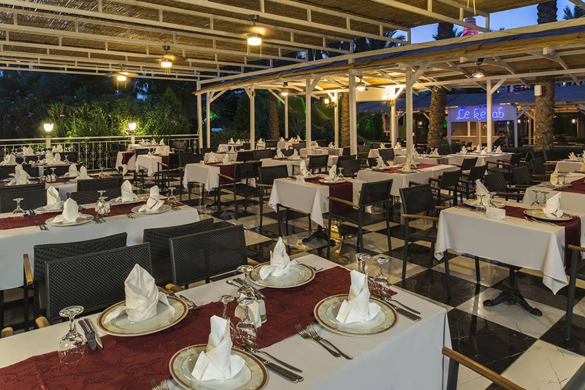 Außenbereich des Delphin Diva Premiere Hotels mit mehreren gedeckten Tischen.
