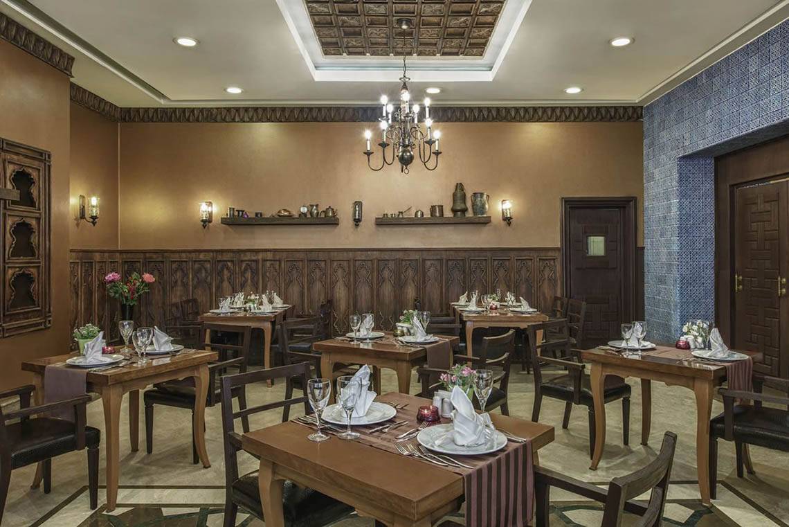 Innenansicht des Restaurants im Delphin Diva Premiere Hotel mit gedeckten Tischen und einer Kronleuchter.