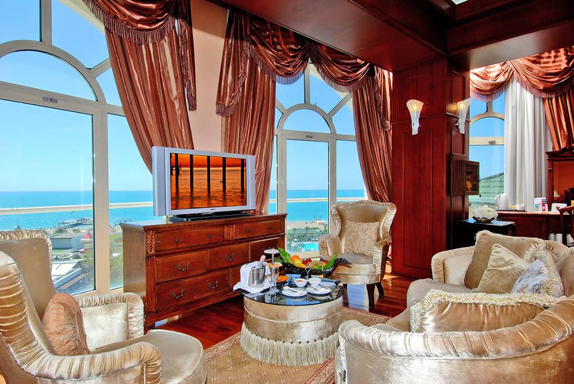 Wohnzimmer der Delphin Diva Premiere Suite mit Meerblick, Fernseher und Tisch mit Obst.