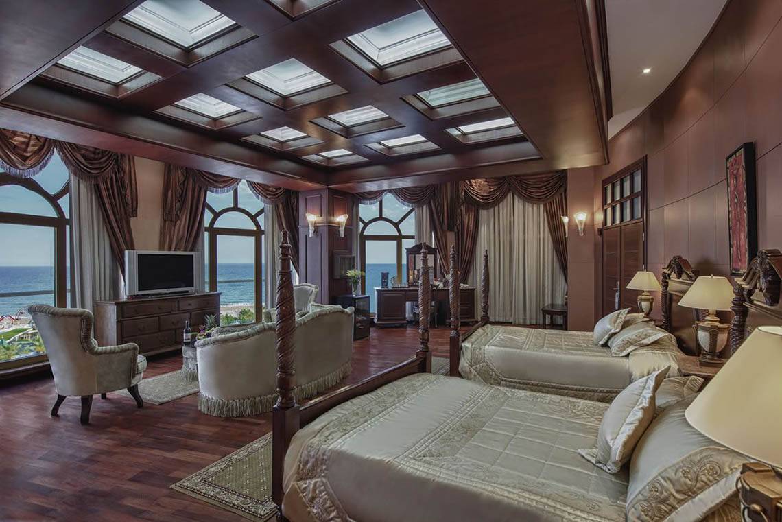 Suite Zimmer im Delphin Diva Premiere Hotel mit Meerblick, zwei Betten, Sesseln und Fernseher.