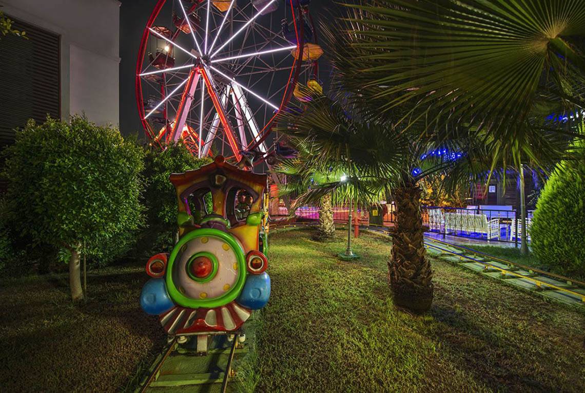 Die Delphin Diva Premiere Nacht Achterbahn mit einem Riesenrad im Hintergrund.