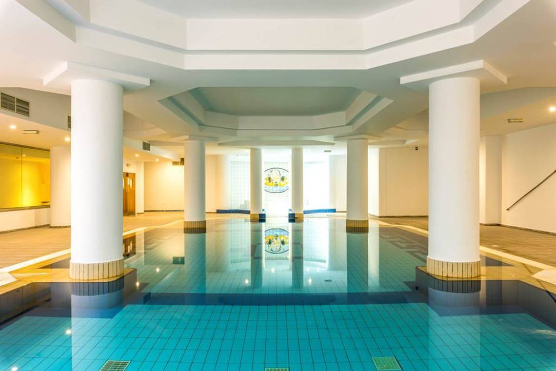 Innenpool des Nissiana Hotels mit blauen Fliesen und weißen Säulen.