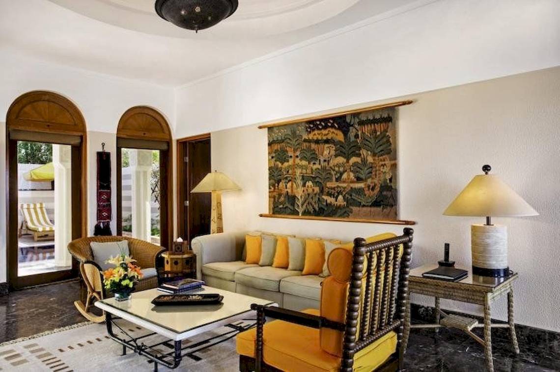 Wohnzimmer im Oberoi Beach Resort mit Sofa, Stühlen, Tisch und Wanddekoration.