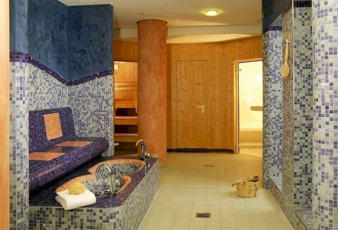 Saunabereich im NH Berlin Alexanderplatz Hotel mit gefliesten Wänden und einer Badewanne.