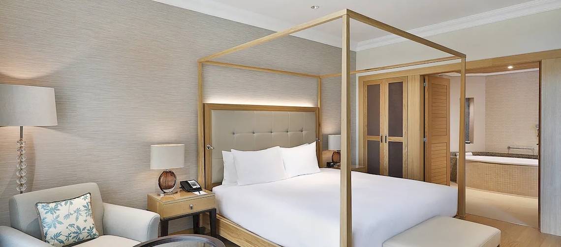 Ein elegantes Hotelzimmer im Hilton Cabo Verde Sal Resort mit einem Himmelbett, einer Kommode und einem Badezimmer.