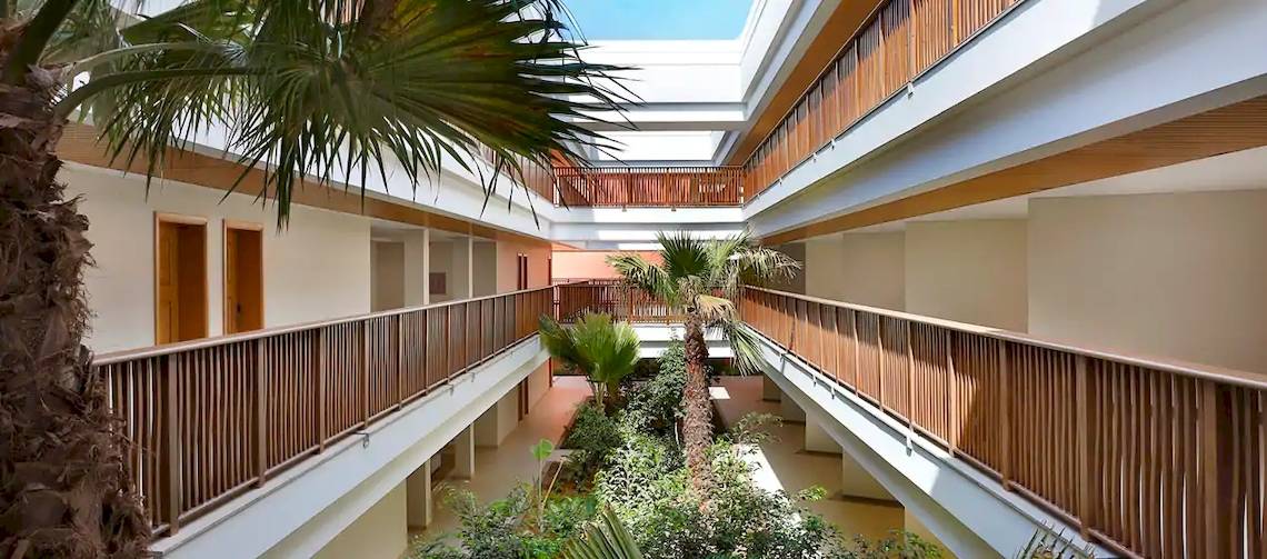 Innenhof des Hilton Cabo Verde Sal Resorts mit Holzbalkonen, Palmen und Pflanzen.
