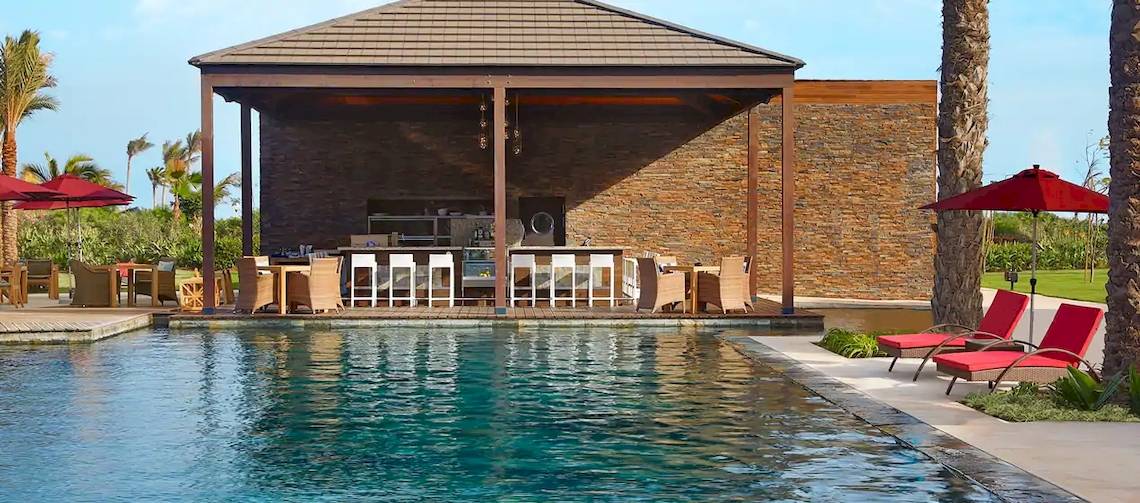 Poolbar des Hilton Cabo Verde Sal Resorts mit Lounge-Stuhl und Sonnenschirm.