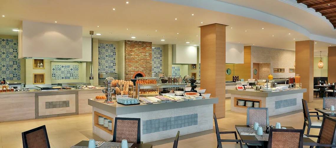 Innenansicht des Restaurants im Hilton Cabo Verde Sal Resort mit Buffet und Tischen.