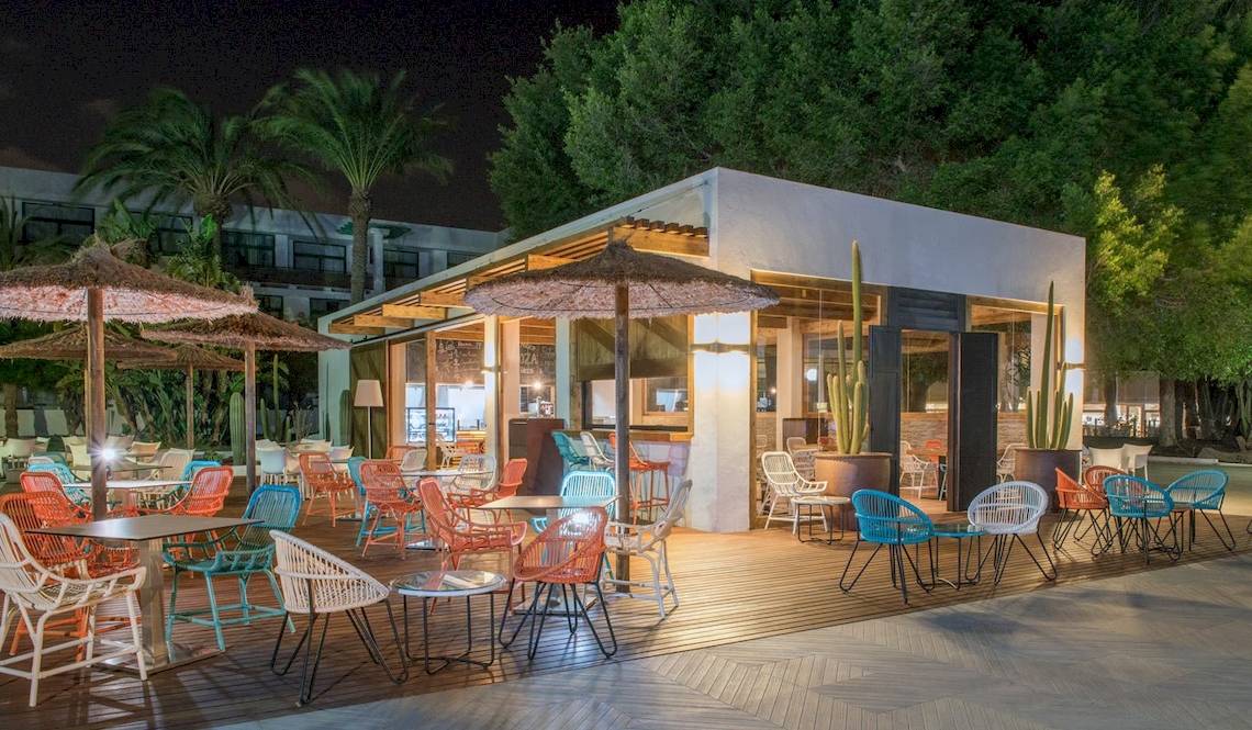 Außenbereich des H10 Lanzarote Princess Hotels bei Nacht mit bunten Stühlen und Tischen.