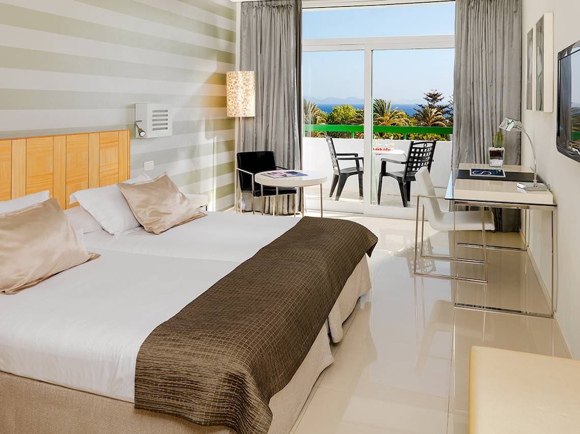 Innenansicht eines Hotelzimmers im H10 Lanzarote Princess mit Blick auf die Terrasse und das Meer.