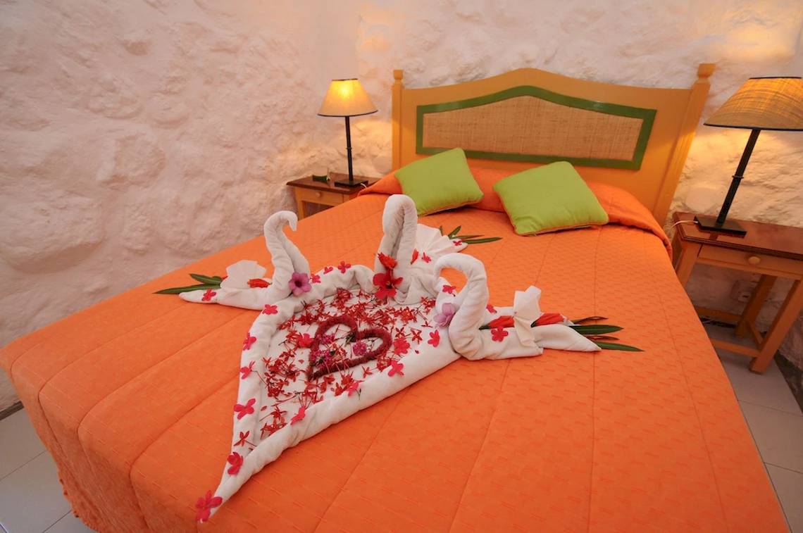 Hotelzimmer im Casuarina Resort & Spa mit orangem Bett und Blumendekoration.