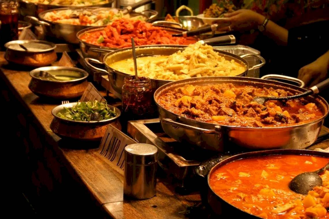Ein Buffettisch mit verschiedenen Gerichten in Metallschüsseln und Töpfen.