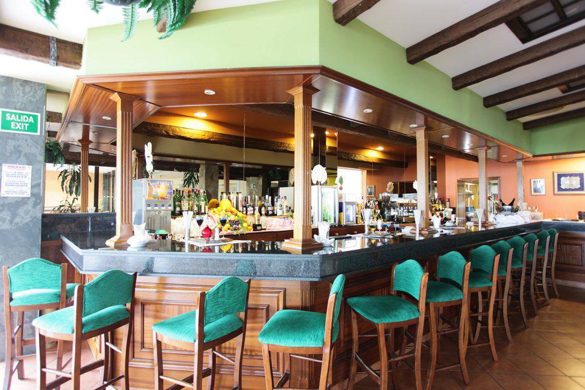 Barbereich im AluaSoul Orotava Valley Hotel mit grünen Stühlen und einer thematisch gestalteten Theke.