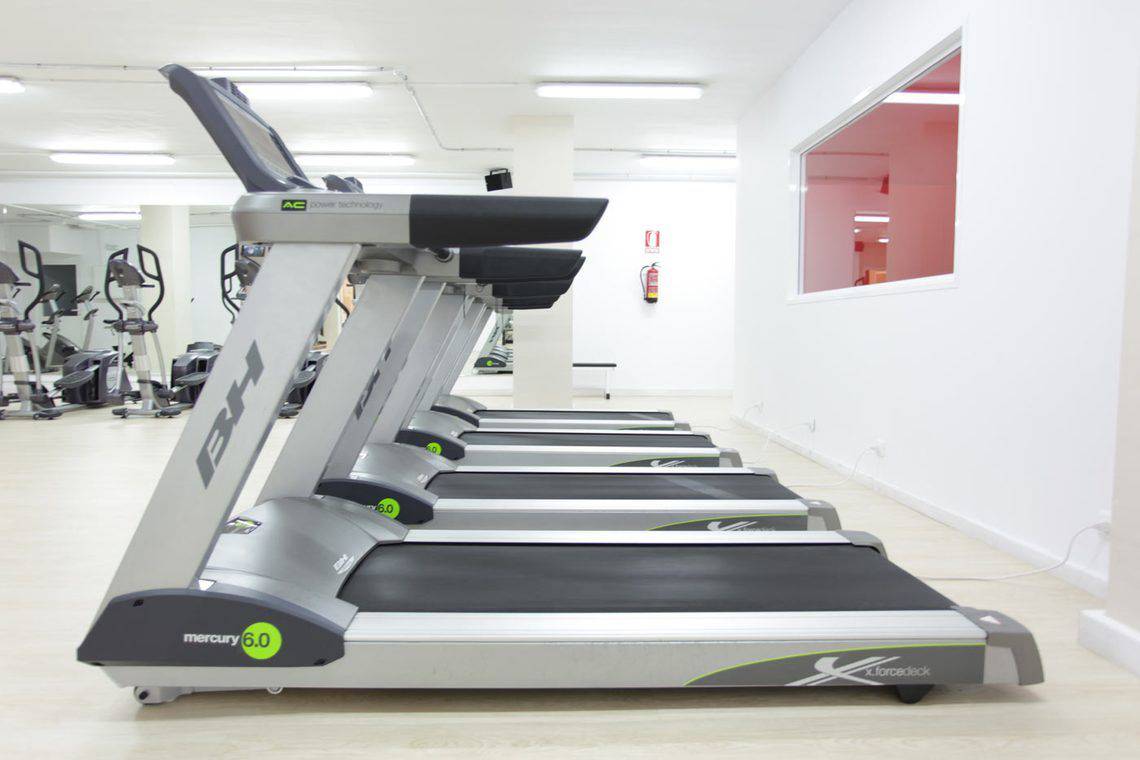 Fitnessstudio mit einer Reihe von Laufbändern in einer Reihe nebeneinander.