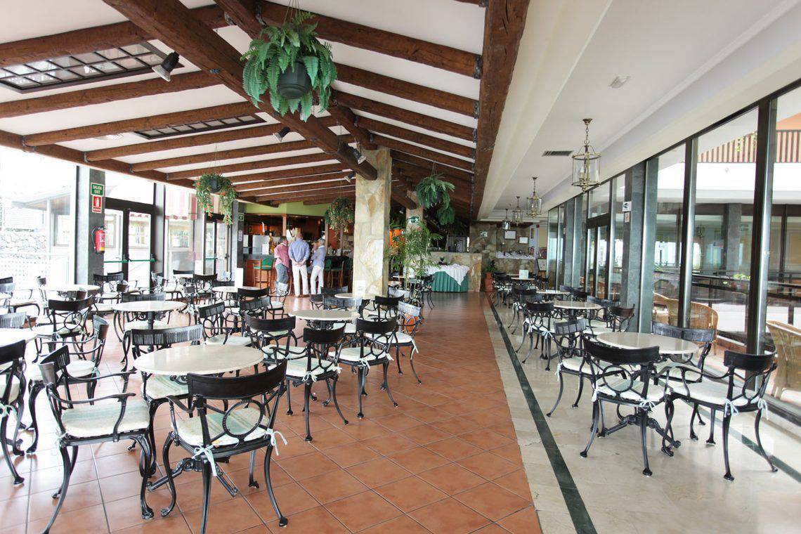 Innenbereich des AluaSoul Orotava Valley Hotels mit Tisch und Stühlen und Holzbalken an der Decke