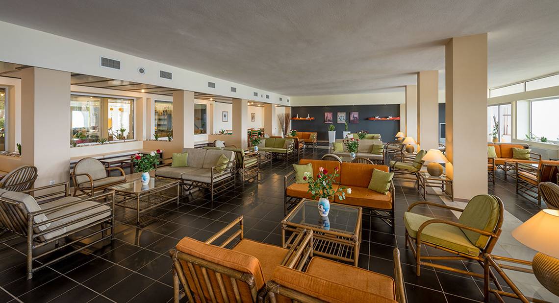 Lobbybereich des Pavlina Beach Hotels mit Möbeln und Blumenarrangements.