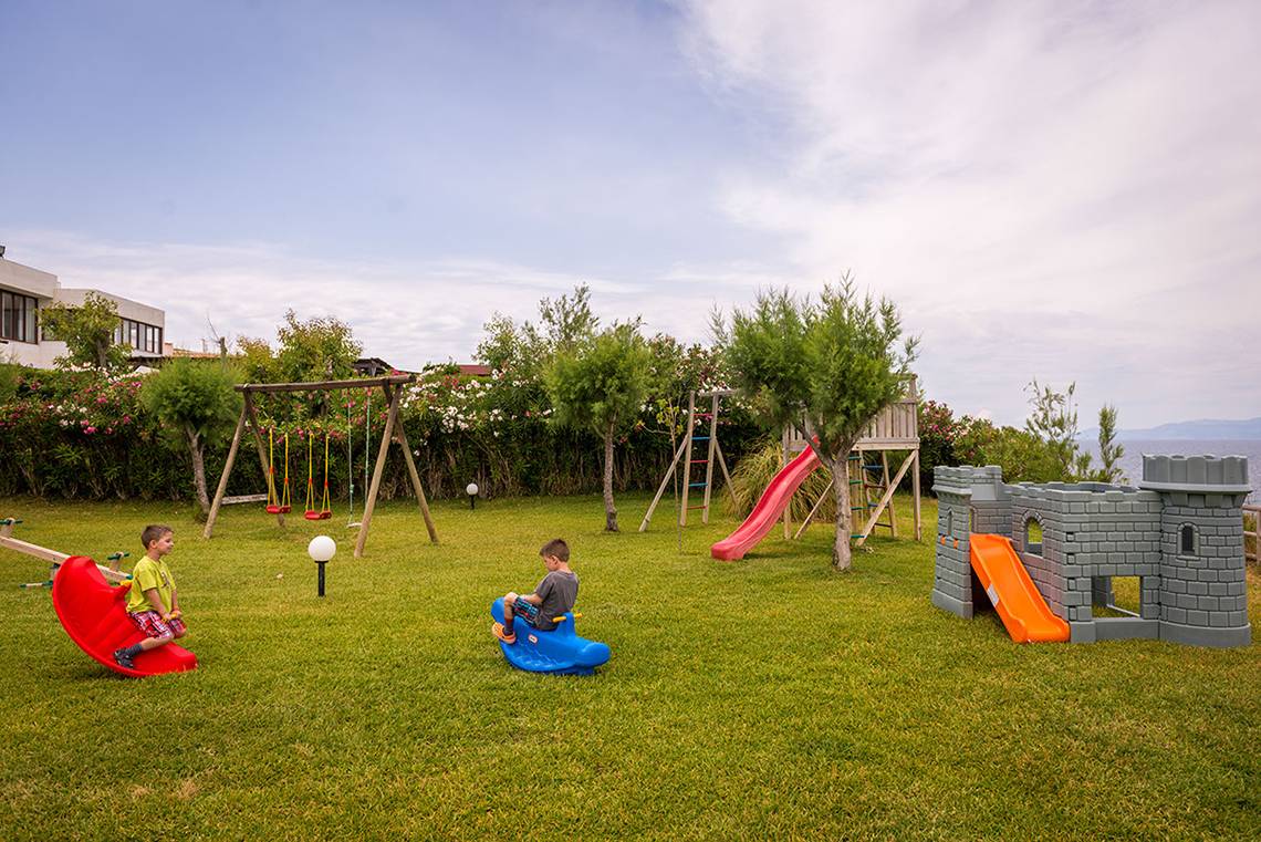 Zwei Kinder spielen auf einem Spielplatz im Freien im Pavlina Beach Hotel.