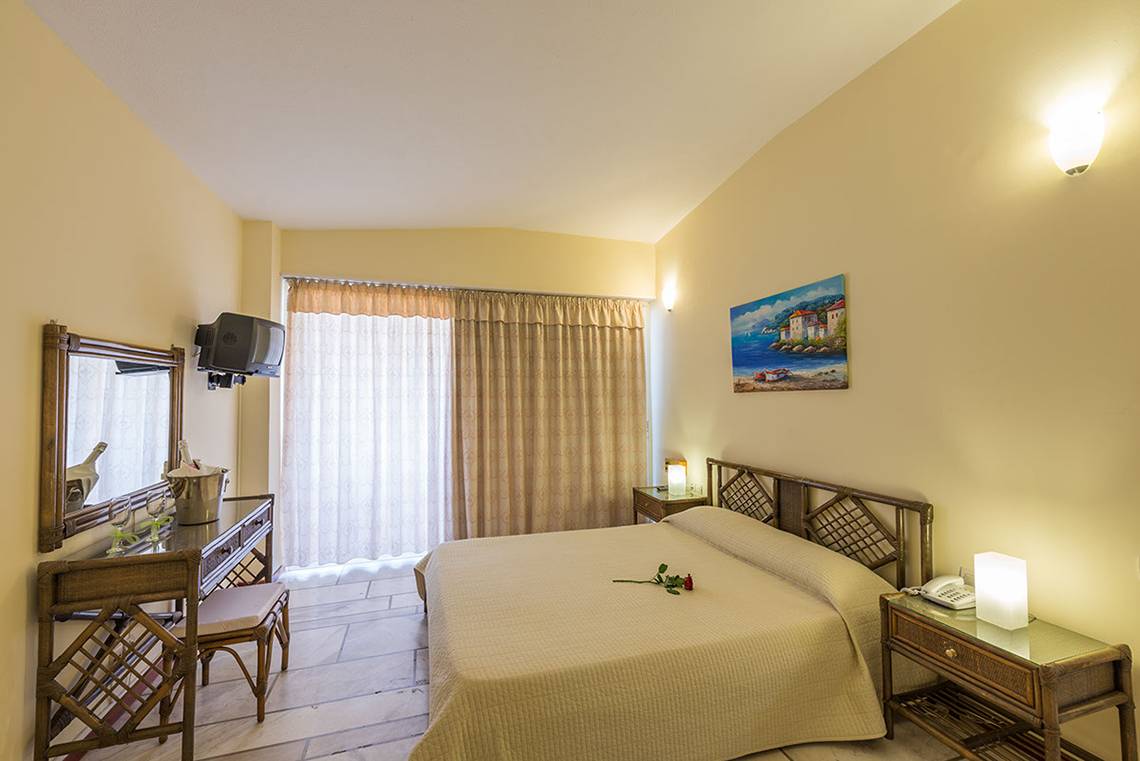 Hotelzimmer im Pavlina Beach Hotel mit Bett, Fernseher, Spiegel und Dekor.