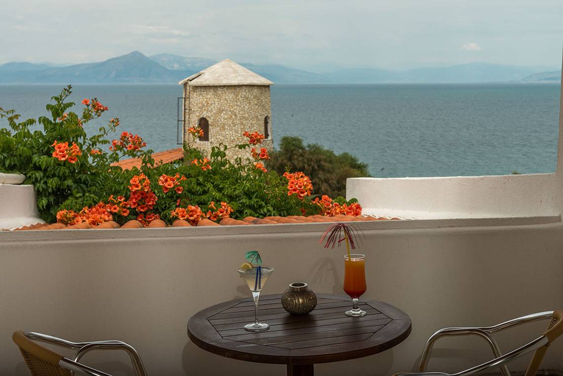 Terrasse des Pavlina Beach Hotels mit Blick auf das Meer und eine Steinstruktur.