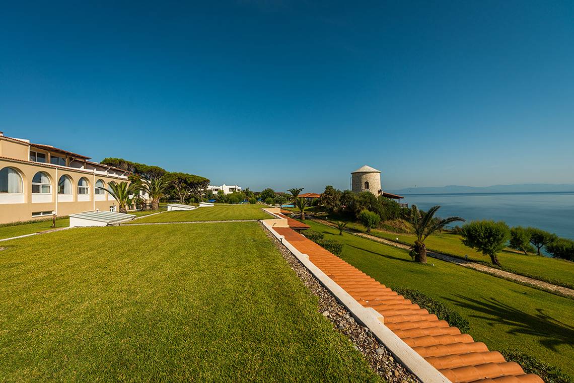 Außenansicht des Pavlina Beach Hotels mit Rasen, Gebäuden und Meer im Hintergrund