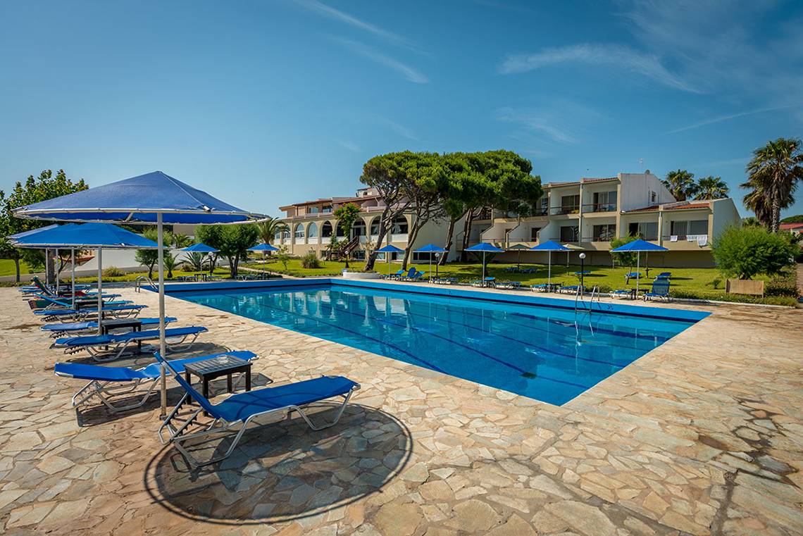 Außenpool des Pavlina Beach Hotels mit Sonnenliegen und Sonnenschirmen.