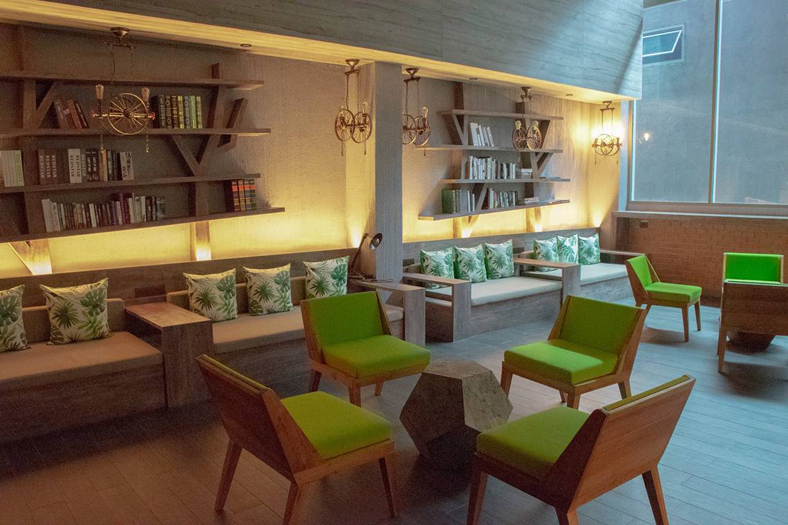 Lobby im Kalima Resort & Villas Khao Lak mit grünen Möbeln und Bücherregalen