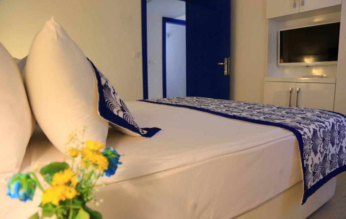Innenansicht eines Hotelzimmers mit Bett, Kissen, Fernseher und Tür im LABRANDA Ephesus Princess Hotel.