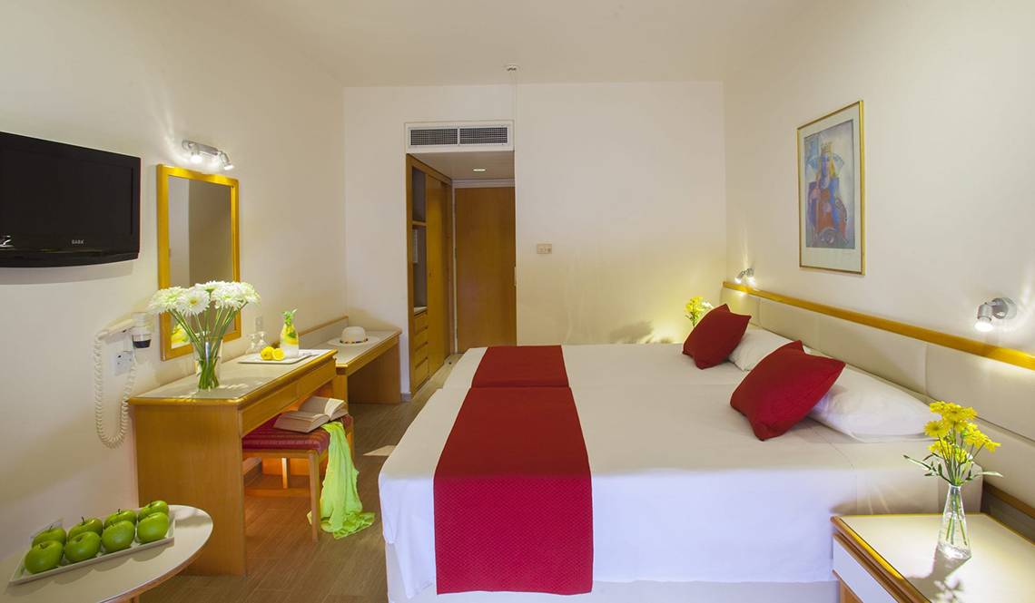 Hotelzimmer im Queens Bay mit zwei Betten, Dekor und Einrichtungsgegenständen.