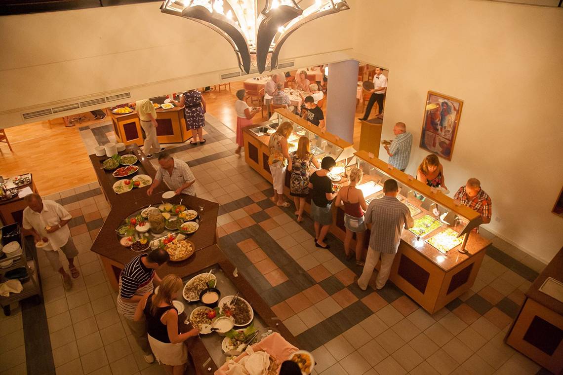 Buffet im Hotel Queens Bay mit verschiedenen Speisen und Gästen, die essen.