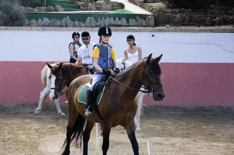 Vier Leute reiten Pferde auf dem Hof des Sun Club El Dorado Hotels.
