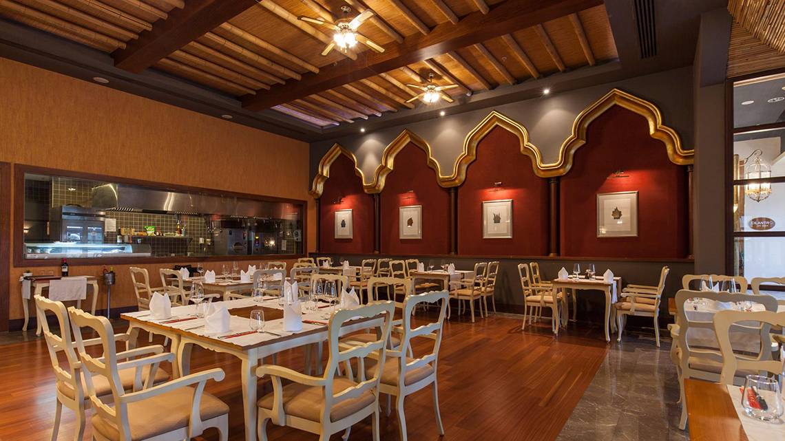Innenbereich des Restaurants im Kempinski Hotel The Dome Belek mit Holzboden und weißen Stühlen.