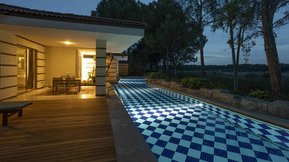 Nachtansicht des Infinity-Pools des Kempinski Hotel The Dome Belek mit beleuchteter Terrasse.