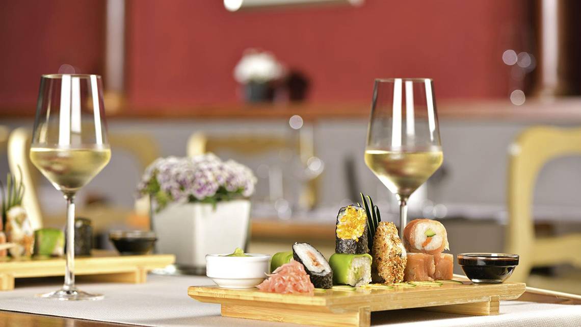 Ein Tisch mit Sushi-Platten, Wein und Weinglas in einem Restaurant.
