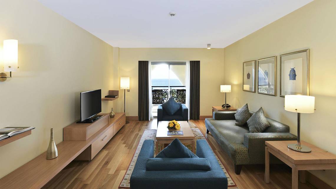 Wohnzimmer der Hotelsuite im Kempinski Hotel The Dome Belek mit Fernseher, Sofas, Couchtisch und Lampen.