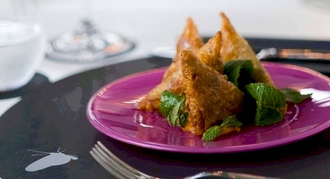 Eine violette Platte mit frittierten Dreiecken und Minzblättern, serviert im Barcelo Raval Hotel.