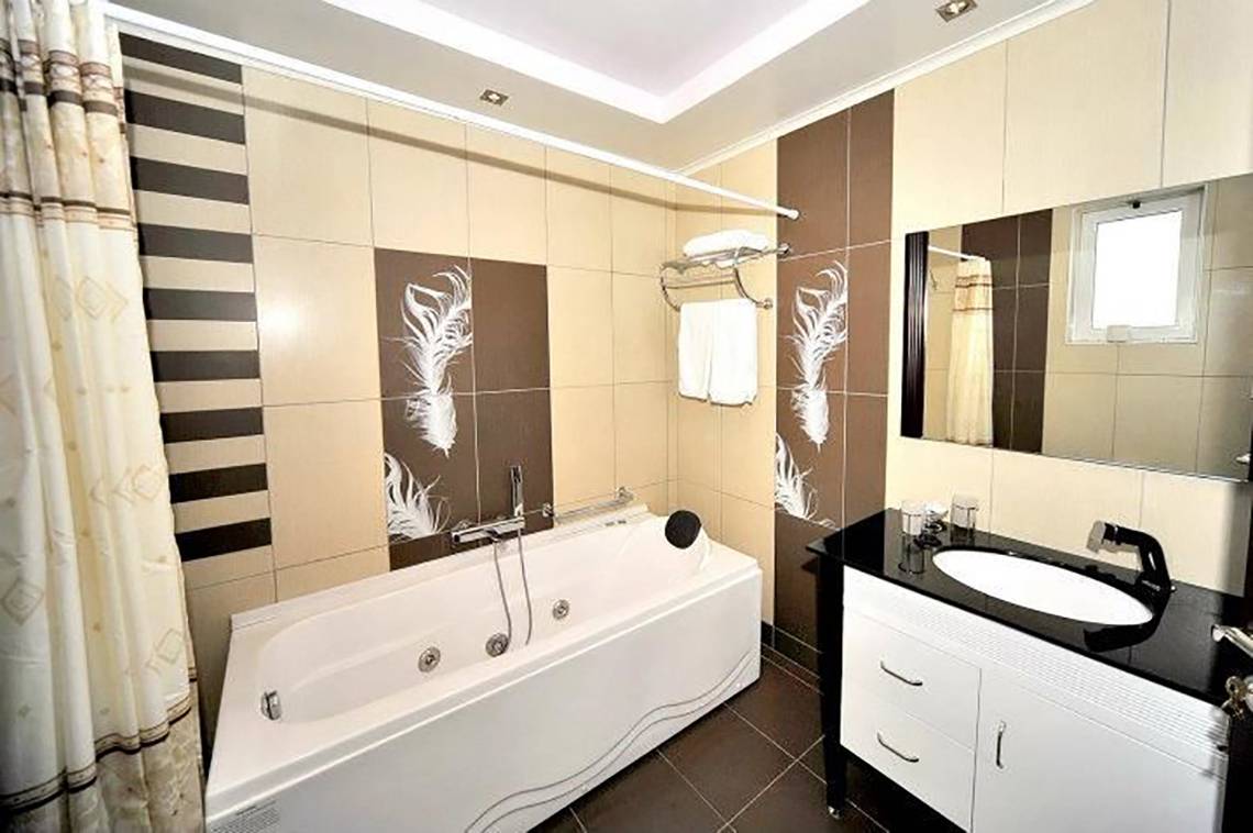 Badezimmer im Gaia Palace Hotel mit Badewanne und modernem Design.