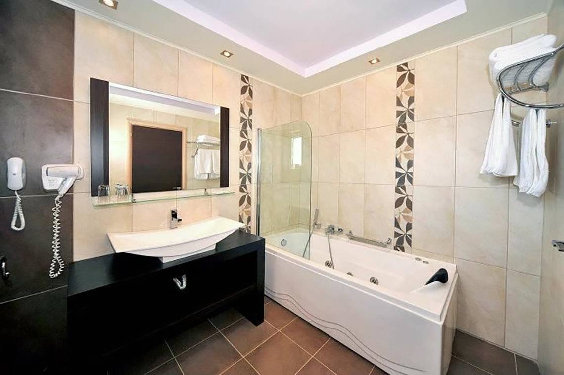 Badezimmer im Gaia Palace Hotel mit Badewanne, Waschbecken und Spiegel