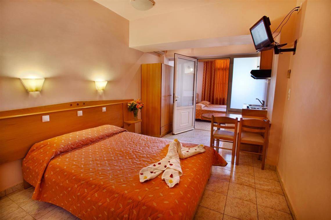 Ilios K. Village Resort Zimmer mit orange Bettdecken und Tischchen